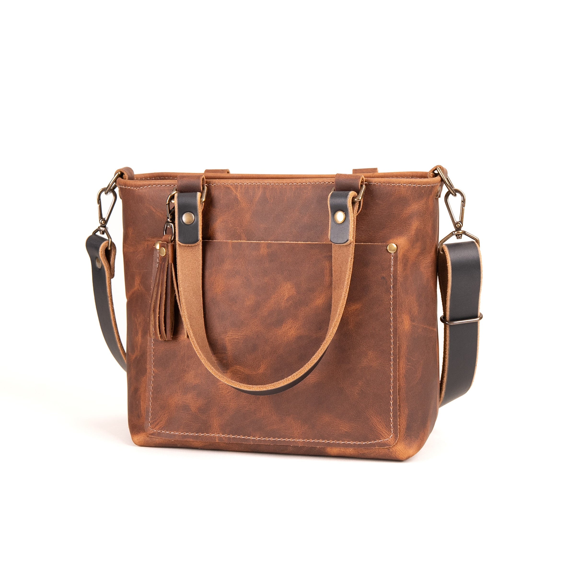 A brown distressed leather tote bag with dual top handles, a front slip pocket, and a detachable shoulder strap, shown on a plain white background.