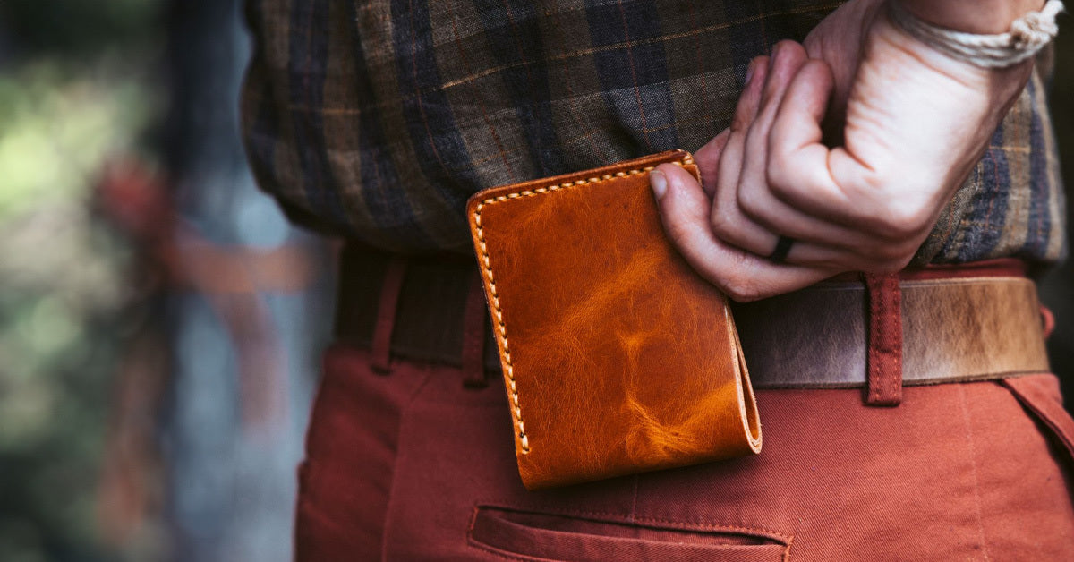 A man tucking a wallet into his back pocket