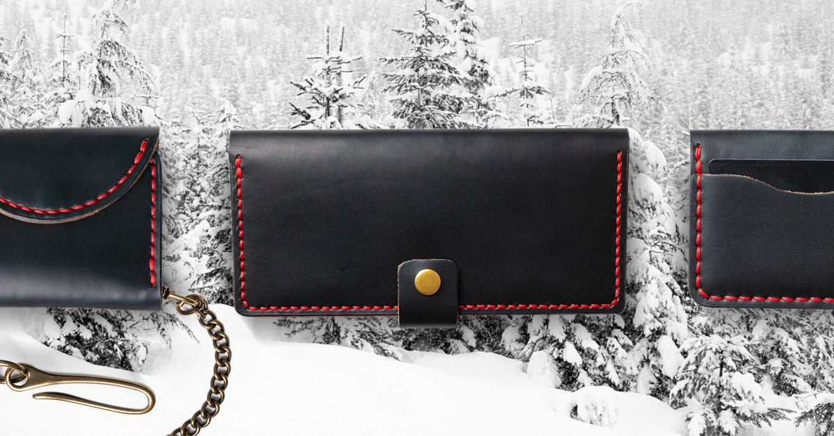 Three handcrafted leather wallets featuring the new black leather and red Tiger thread color combo, situated over a wintery background