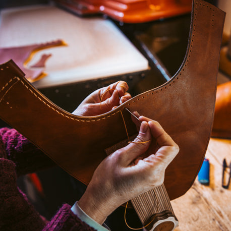 woman sewing leather shoe by hand