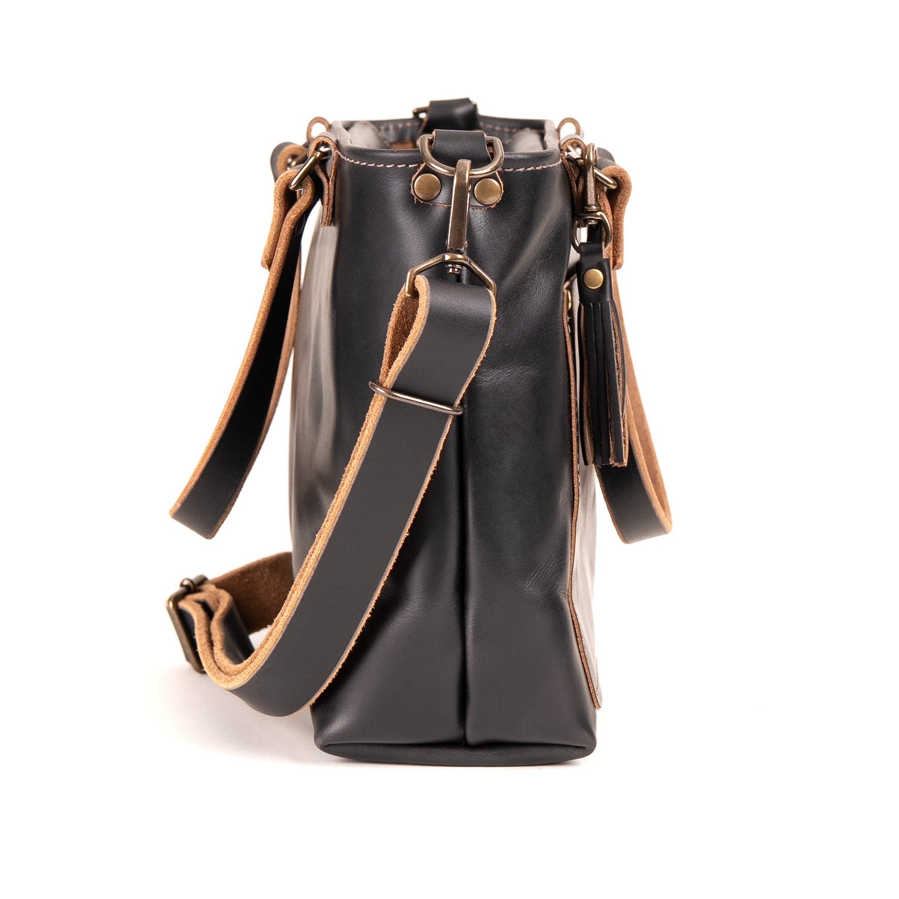 A black leather bucket bag with tan leather trim and a matching adjustable shoulder strap, shown from the back on a white background.