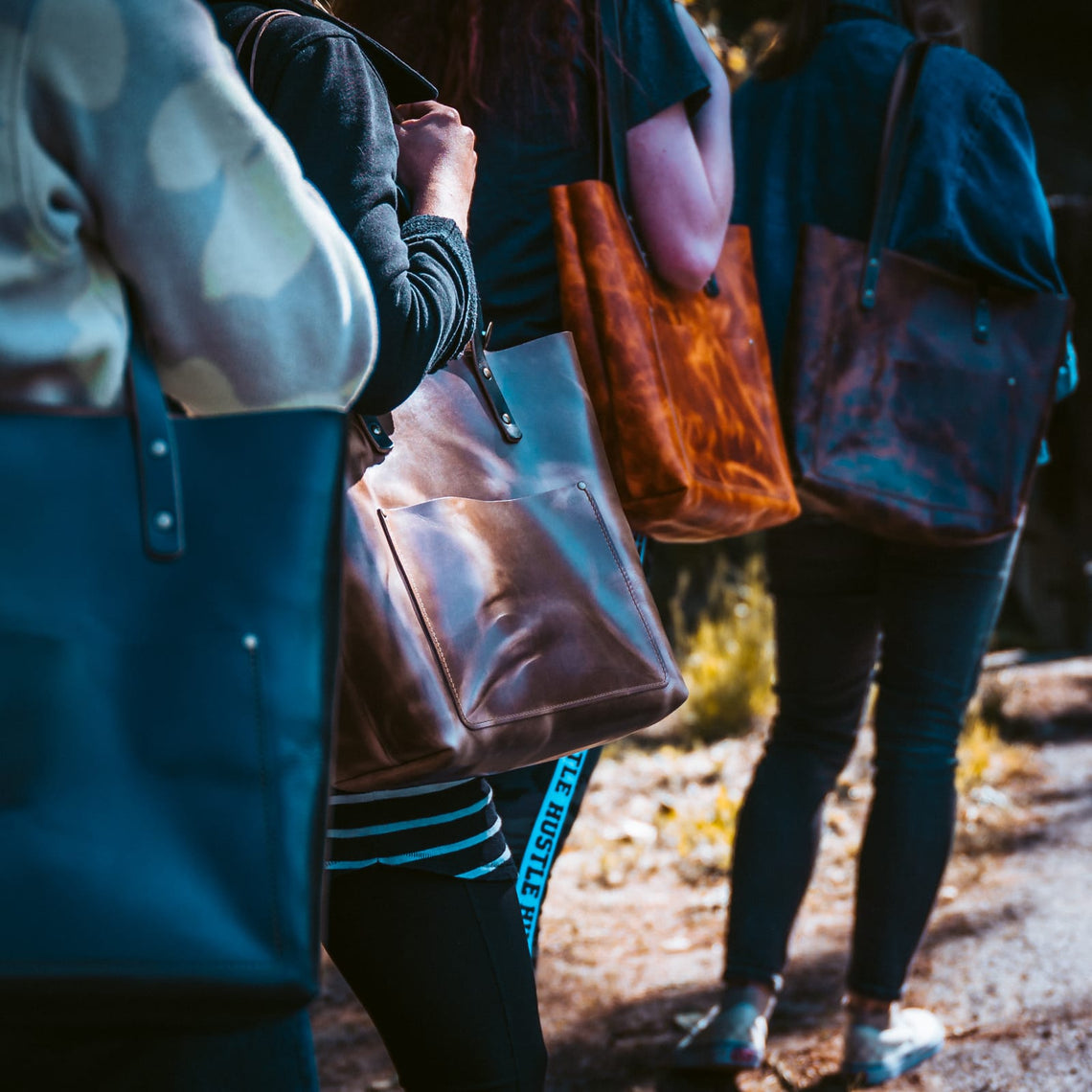 Customers carrying Popov Leather totes in several colours