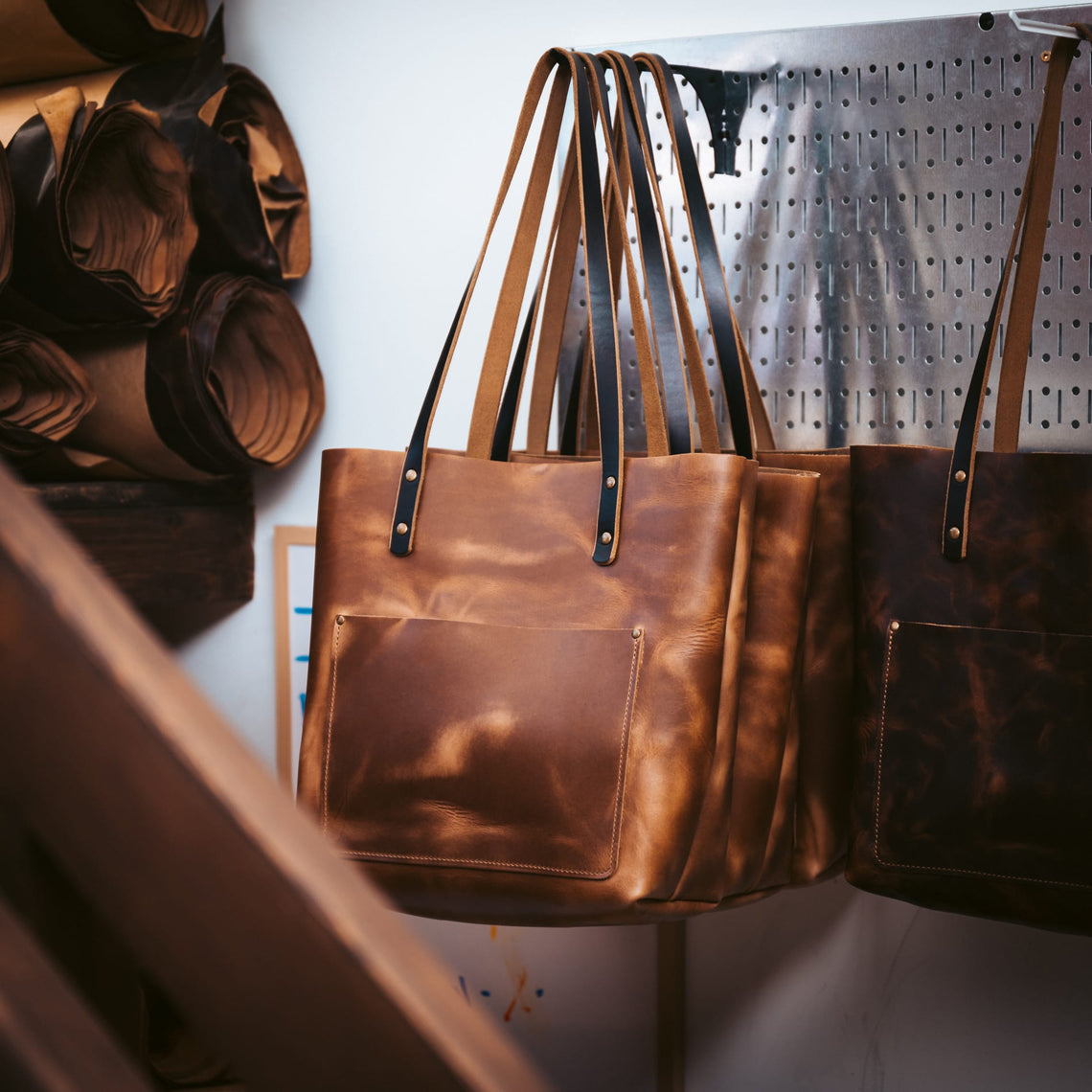 Leather totes hanging on the rack in the Popov Leather workshop